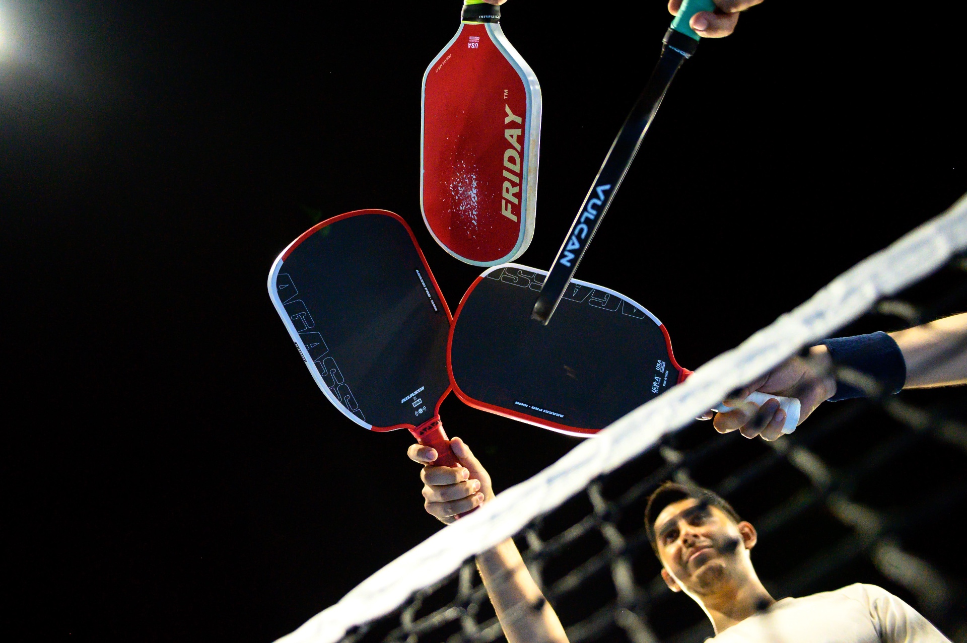 Jugadores de pickleball chocando paletas sobre la red